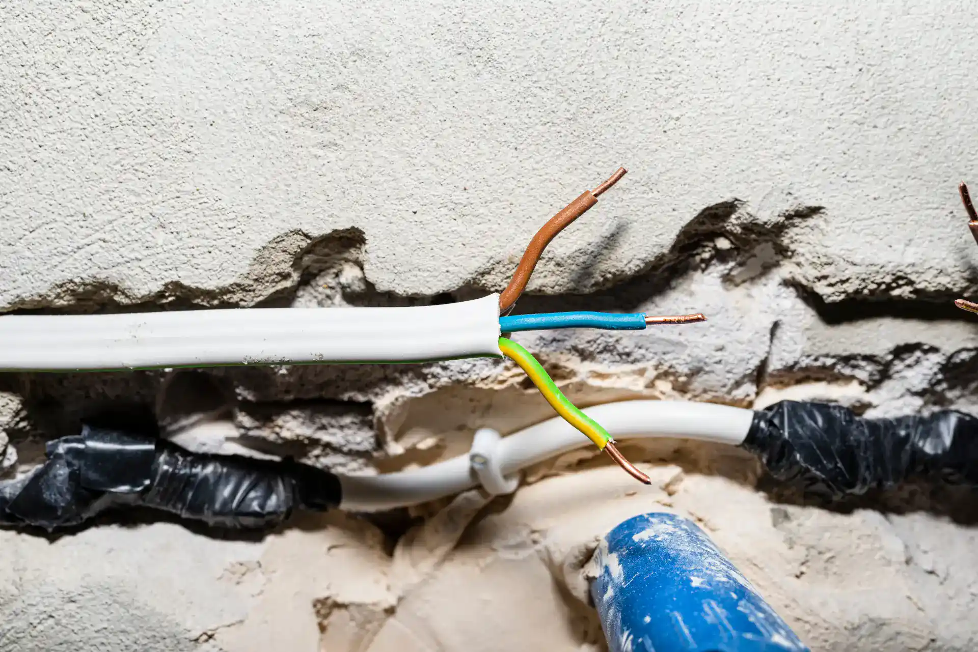 Elektrikerarbejde med synlige ledninger og kabler i væggen.